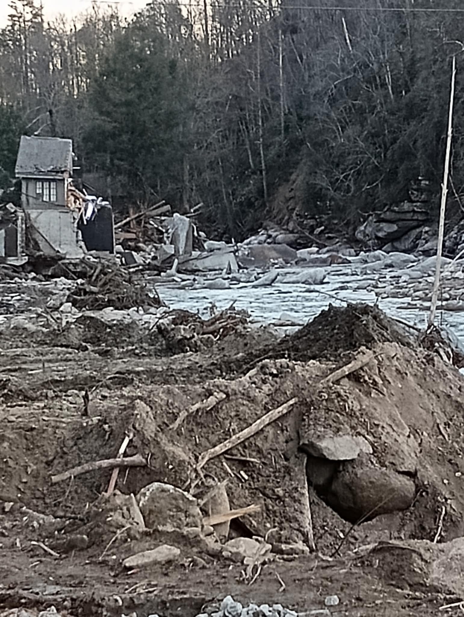 Destroyed creekside structure and debris field after storm flooding